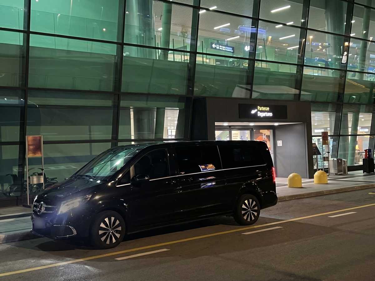 La nostra Mercedes Classe V nera di sera, a fari accesi, davanti all'ingresso Partenze dell'aeroporto di Verona